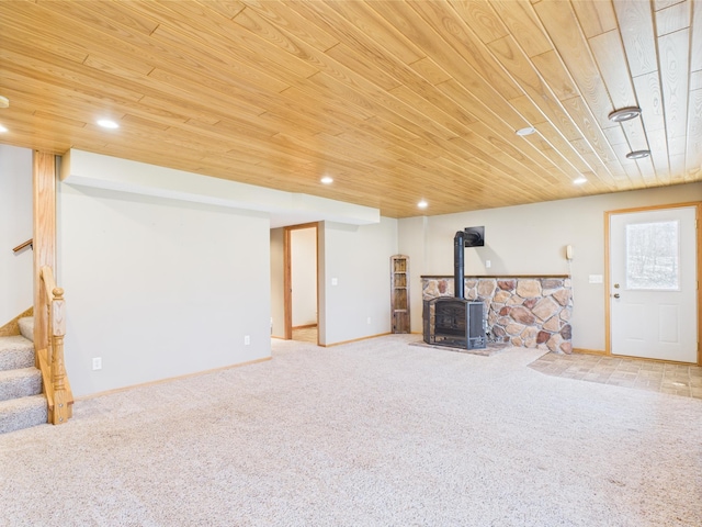 below grade area featuring carpet flooring, stairs, a wood stove, and wooden ceiling