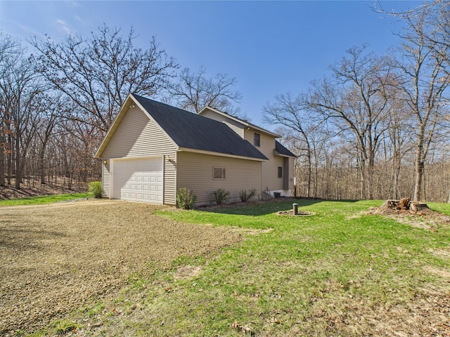 view of side of home featuring a yard, a shingled roof, and a detached garage