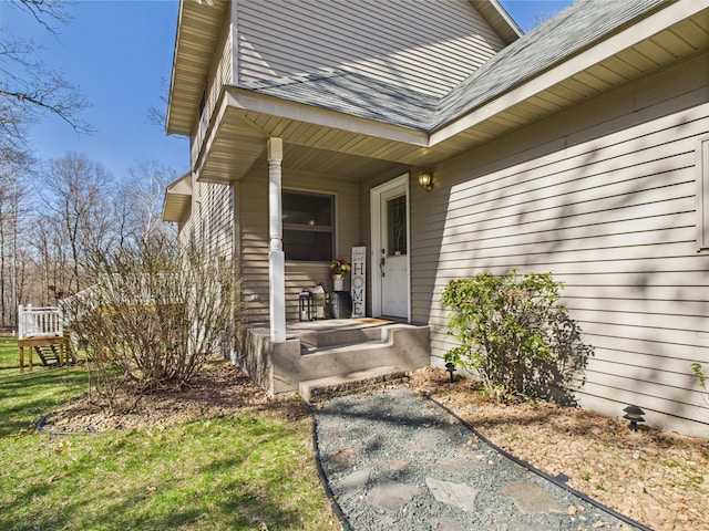 property entrance featuring roof with shingles and a lawn