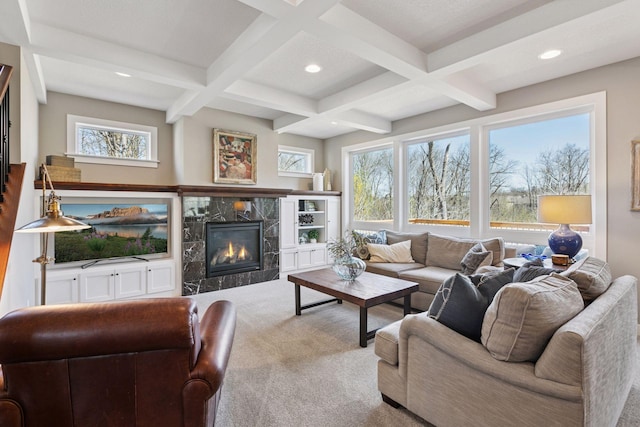 living room with a wealth of natural light, beamed ceiling, carpet flooring, and a premium fireplace