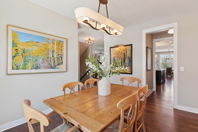dining area with baseboards, a notable chandelier, and dark wood-style floors