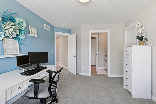 home office with a textured ceiling, visible vents, light carpet, and baseboards