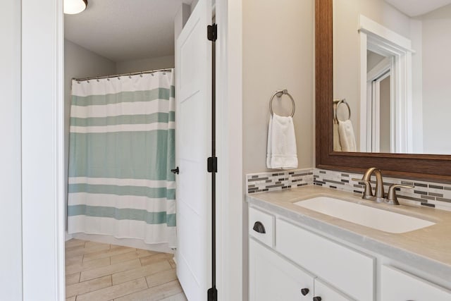 bathroom with backsplash, a shower with shower curtain, and vanity