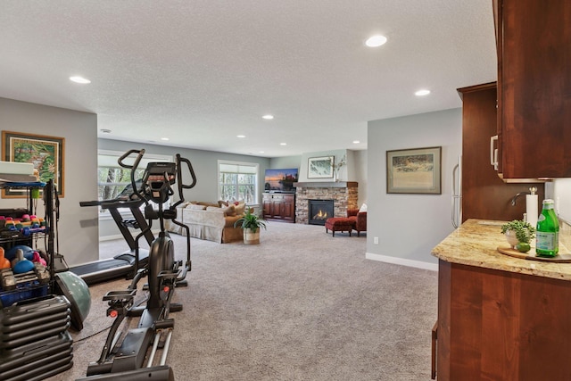 exercise area with carpet flooring, a sink, a textured ceiling, a stone fireplace, and recessed lighting