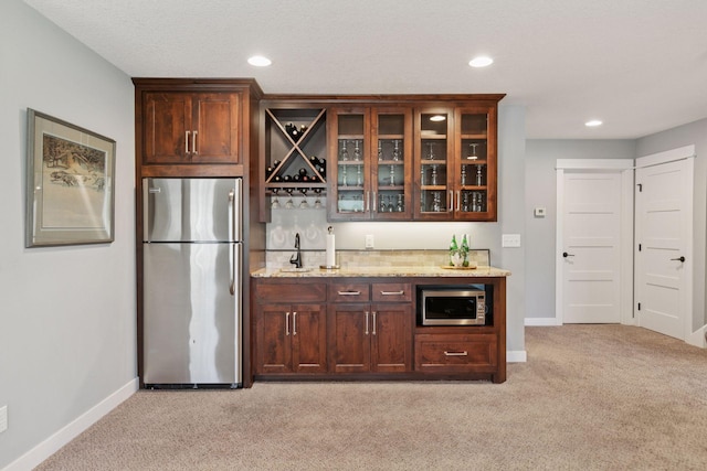 bar with appliances with stainless steel finishes, baseboards, light carpet, and wet bar