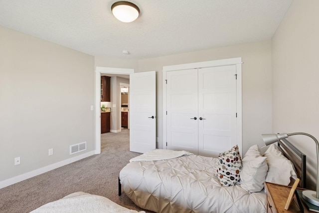 carpeted bedroom with visible vents, baseboards, and a closet