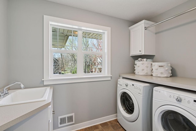 laundry room featuring visible vents, washing machine and dryer, baseboards, a sink, and cabinet space