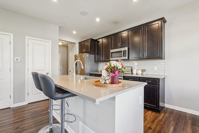 11462 81st Pl N, Maple Grove, MN 55369 - kitchen featuring stainless steel appliances, baseboards, dark wood finished floors, an island with sink, and recessed lighting