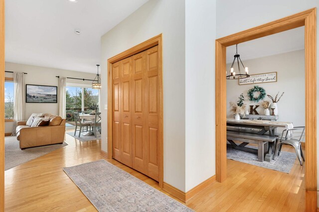 hallway featuring an inviting chandelier and wood finished floors