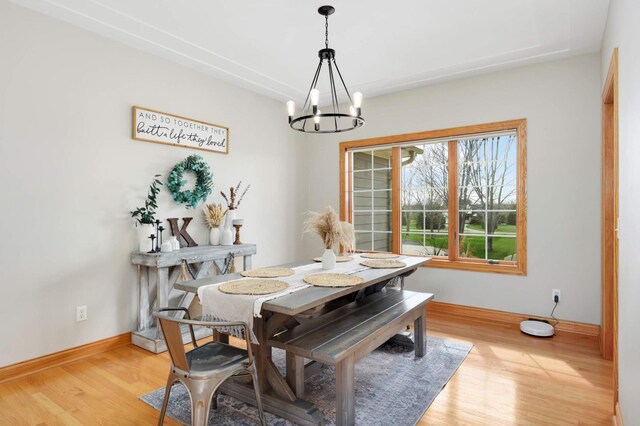 dining area featuring baseboards, light wood-style flooring, and a notable chandelier