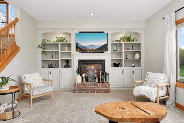living room featuring light colored carpet, plenty of natural light, stairway, and a fireplace