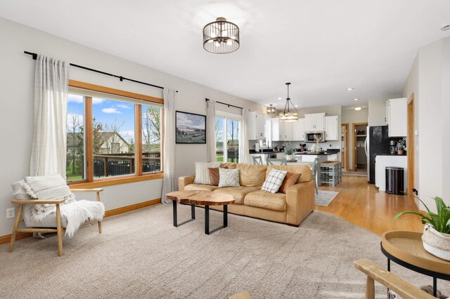 living room featuring recessed lighting, baseboards, a chandelier, and light wood finished floors