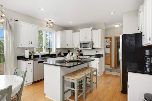 kitchen featuring a sink, white cabinetry, appliances with stainless steel finishes, and a breakfast bar