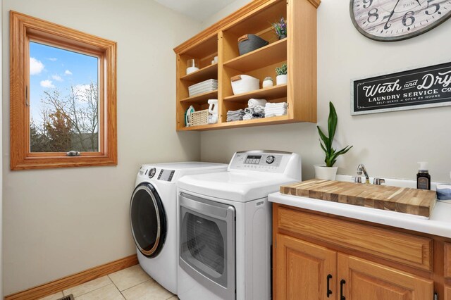 washroom with cabinet space, a sink, separate washer and dryer, baseboards, and light tile patterned floors