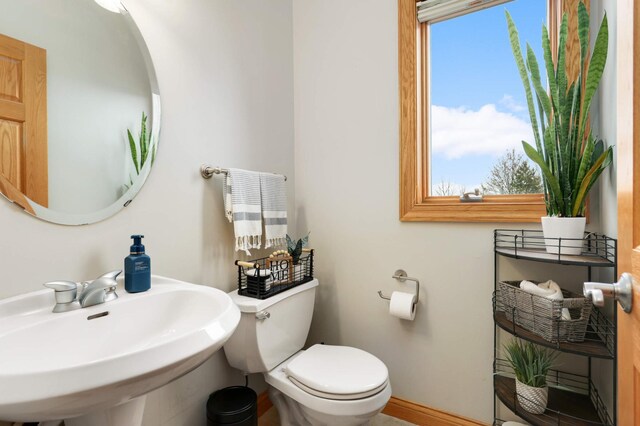 bathroom featuring toilet, baseboards, and a sink