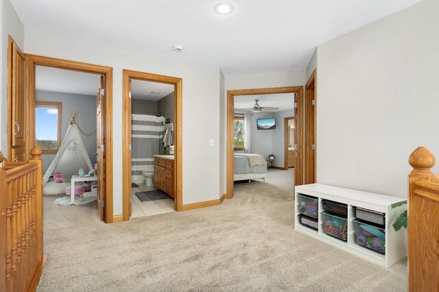 bedroom with baseboards, light carpet, and ensuite bath