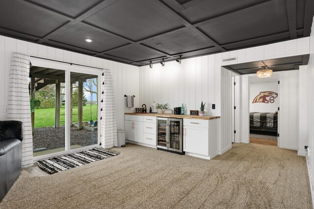 bar featuring light carpet, beverage cooler, wood walls, indoor wet bar, and coffered ceiling