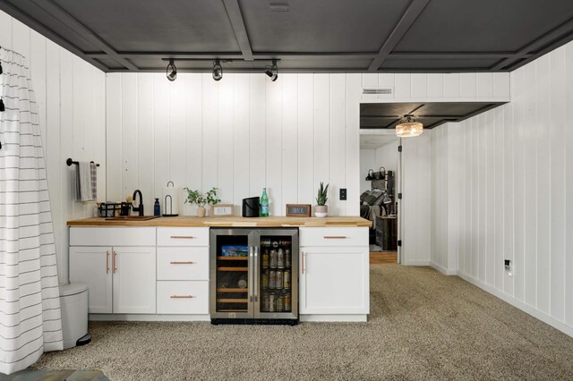 bar with indoor wet bar, a sink, wine cooler, and light colored carpet