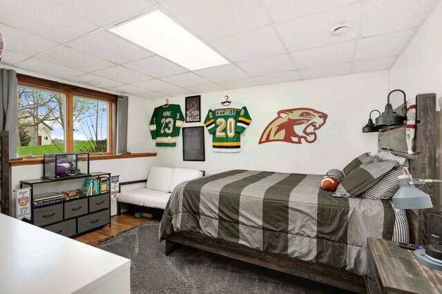 bedroom with wood finished floors and a drop ceiling