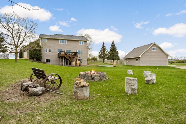 rear view of house with a lawn, a deck, and a fire pit