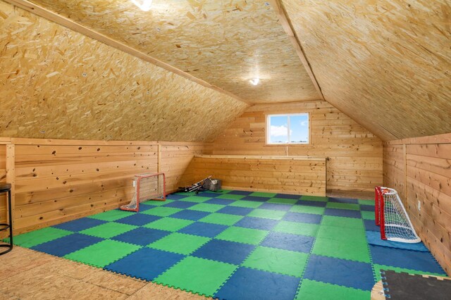 additional living space featuring tile patterned floors, wood walls, and lofted ceiling
