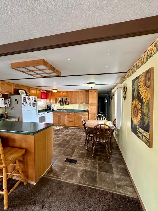 1404 Central Rd, Littlefork, MN 56653 - kitchen featuring dark countertops, a sink, white appliances, brown cabinetry, and visible vents