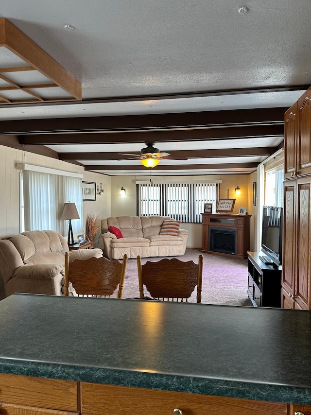 1404 Central Rd, Littlefork, MN 56653 - carpeted living area with a ceiling fan, a textured ceiling, beam ceiling, and a fireplace