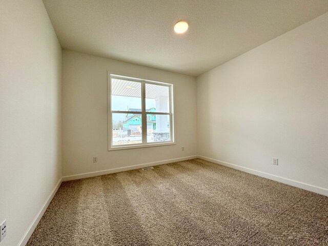 carpeted empty room featuring baseboards