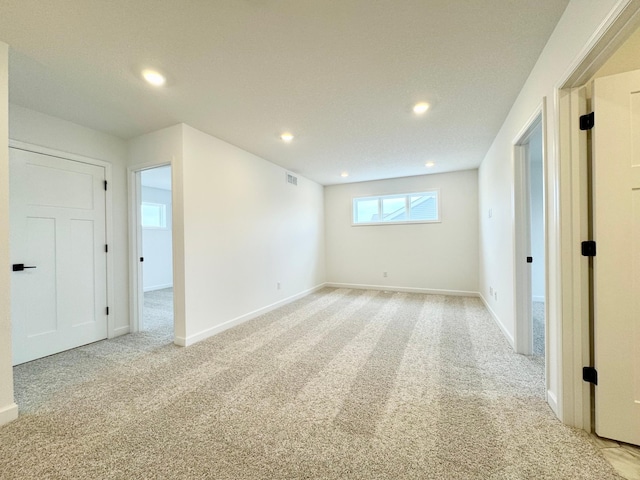 interior space featuring recessed lighting, baseboards, light colored carpet, and visible vents