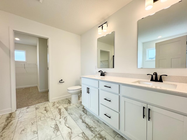 bathroom with double vanity, marble finish floor, toilet, a spacious closet, and a sink