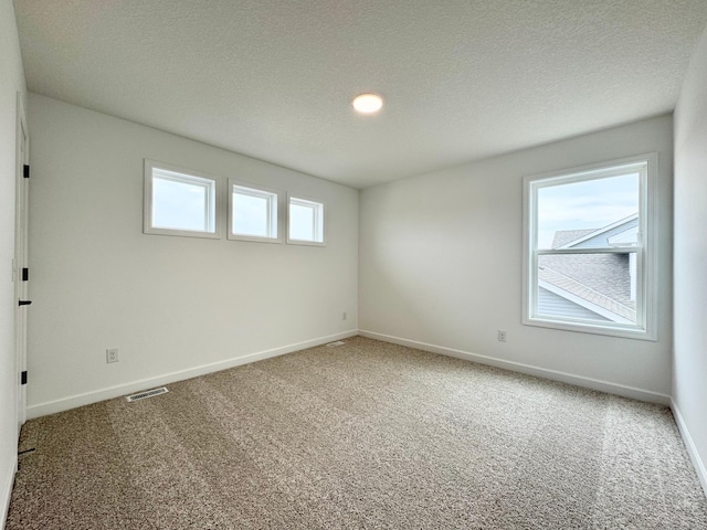 empty room with visible vents, carpet flooring, and a textured ceiling