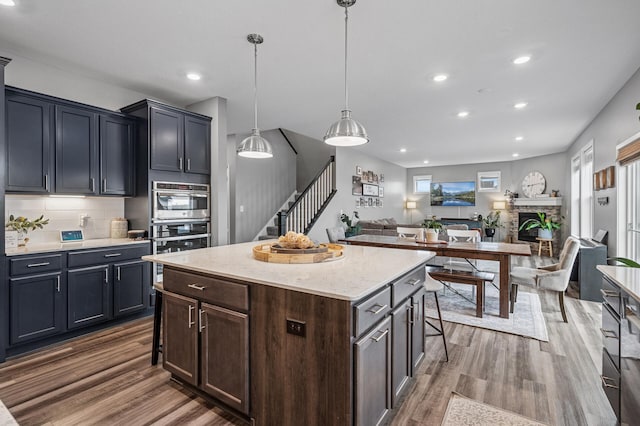 11270 Meadow View Ln, Maple Grove, MN 55311 - kitchen featuring wood finished floors, a fireplace, double oven, recessed lighting, and tasteful backsplash