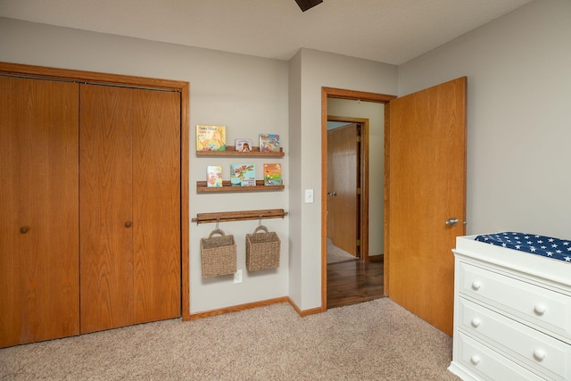 bedroom with baseboards, light colored carpet, and a closet