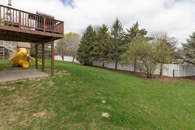 view of yard with a fenced backyard, a playground, and a deck