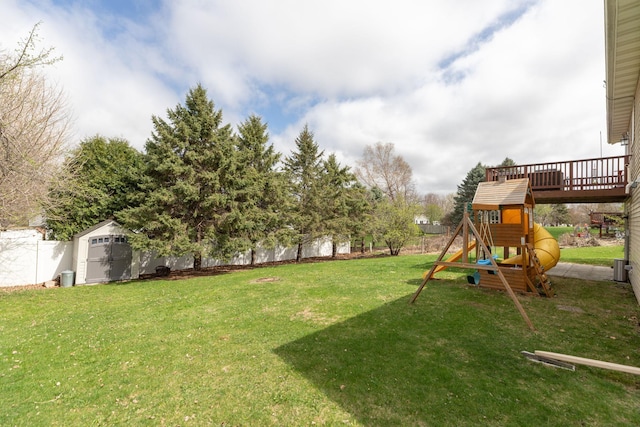 view of yard featuring a storage unit, a fenced backyard, a playground, and an outbuilding