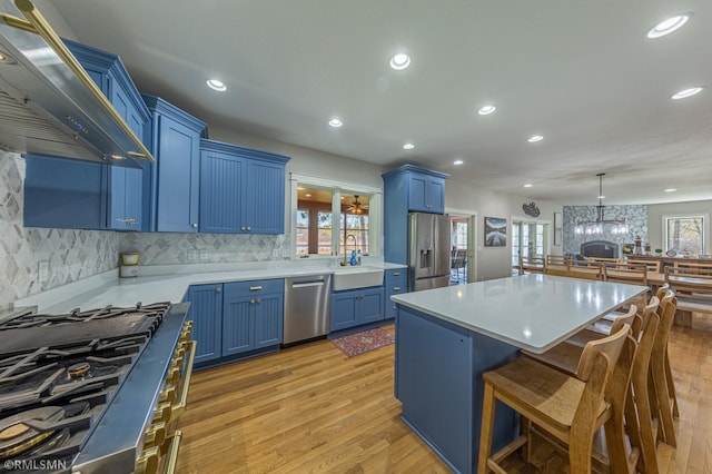 509 Superior Ave, Crosby, MN 56441 - kitchen with a sink, premium range hood, blue cabinets, light wood finished floors, and appliances with stainless steel finishes