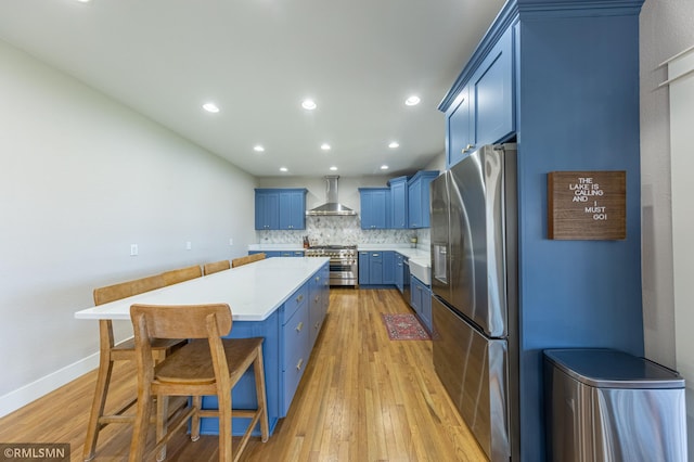 509 Superior Ave, Crosby, MN 56441 - kitchen with decorative backsplash, a kitchen island, blue cabinets, stainless steel appliances, and wall chimney exhaust hood