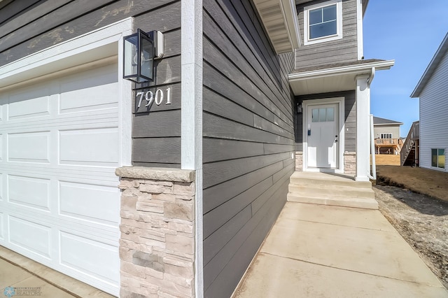 view of exterior entry with a garage and stone siding