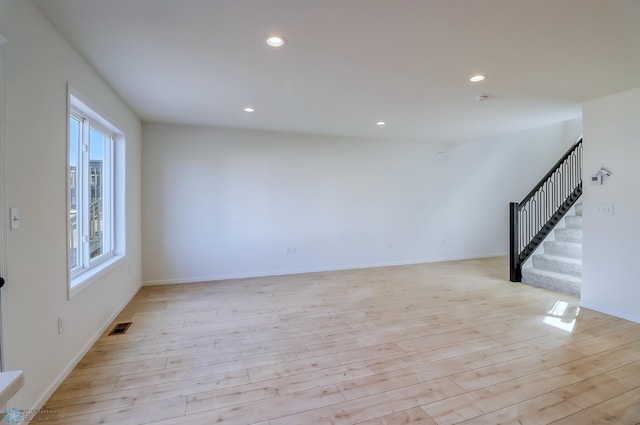 unfurnished living room featuring recessed lighting, baseboards, light wood-type flooring, visible vents, and stairway