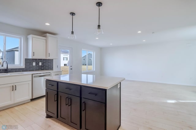 kitchen with a sink, light wood finished floors, white cabinetry, and dishwasher