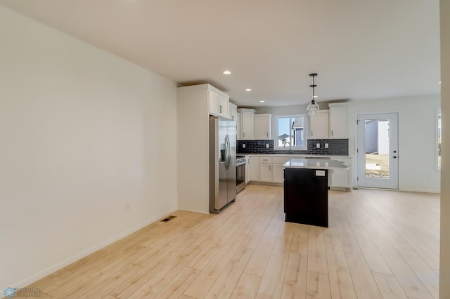kitchen with a sink, stainless steel fridge with ice dispenser, light countertops, white cabinetry, and tasteful backsplash