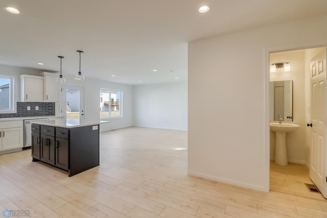 kitchen with backsplash, dishwasher, light countertops, white cabinets, and recessed lighting