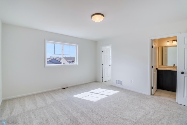 unfurnished bedroom with a sink, baseboards, visible vents, and light colored carpet