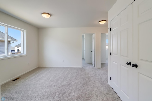 unfurnished room featuring baseboards, light colored carpet, and visible vents