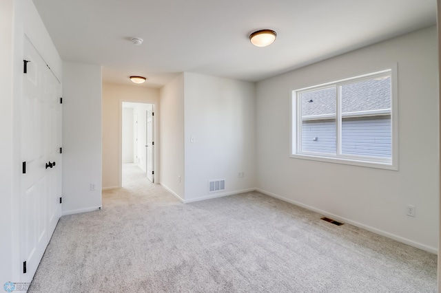 carpeted empty room featuring baseboards and visible vents