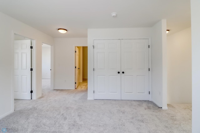 unfurnished bedroom with carpet floors, baseboards, and a closet