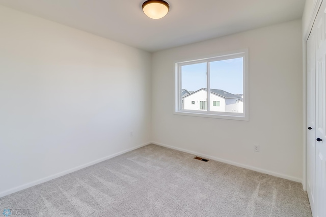 unfurnished room with visible vents, baseboards, and light colored carpet