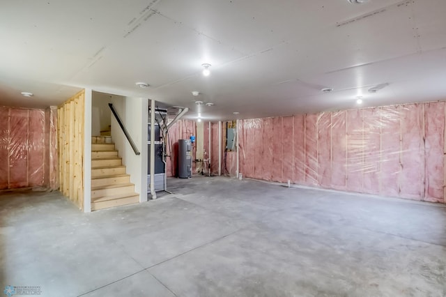 unfinished basement featuring electric panel, stairway, and electric water heater