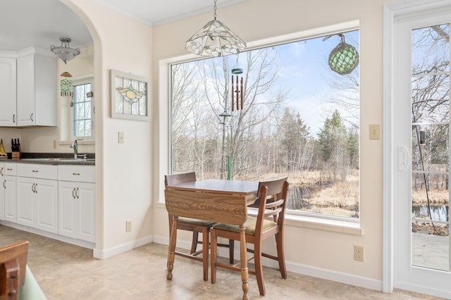 dining area with baseboards, arched walkways, plenty of natural light, and crown molding