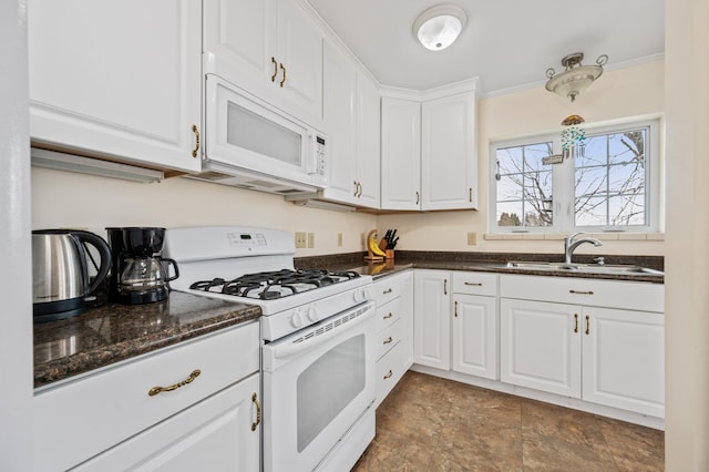 kitchen featuring white appliances, stone finish floor, dark stone counters, white cabinetry, and a sink